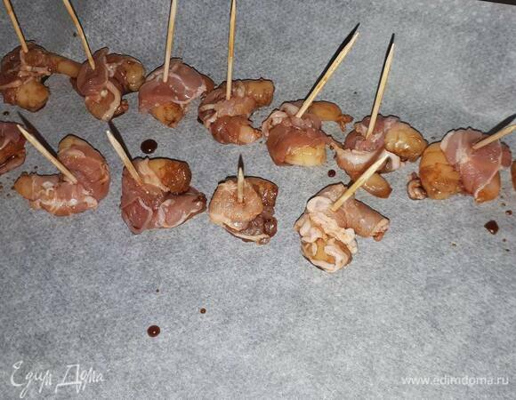 Разрежьте нарезку бекона на 2–3 части. Оберните кусочек бекона вокруг креветки, зафиксируйте зубочисткой и выложите на противень. Выпекайте в разогретой до 200°C духовке в режиме «Гриль» 8–10 минут.