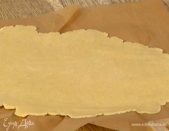 Вымесить тесто руками и сформировать из него шар, затем поместить между двумя листами бумаги для выпечки и раскатать в пласт толщиной 2–3 мм.