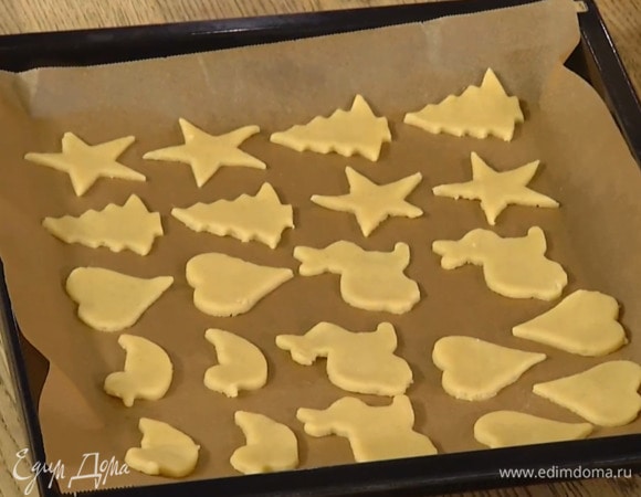 Кондитерскими формами вырезать из теста четное количество фигурок и выложить на выстеленный бумагой для выпечки противень.