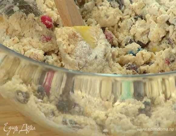 Оставшуюся муку перемешать с содой, шоколадными каплями, половиной разноцветного драже, измельченными орехами, добавить сливочно-сахарную массу и вымешать тесто лопаткой.