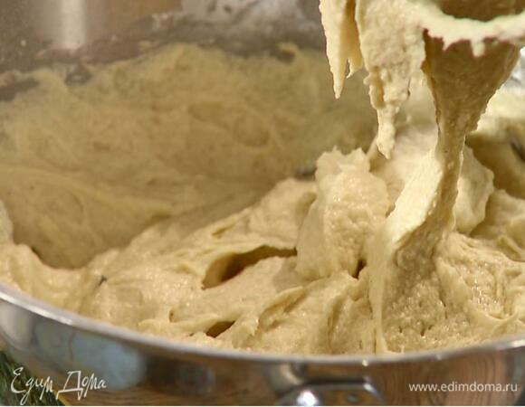 Продолжая взбивать, небольшими порциями всыпать половину муки с разрыхлителем, влить айран, частями всыпать оставшуюся муку и вымешать, затем всыпать шоколадные пуговицы и вымешать тесто еще немного.