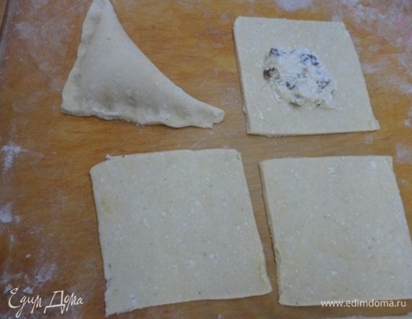 Тесто разделить на две части и каждую раскатать на посыпанном мукой столе в прямоугольник. Затем каждый нарежьте на 6 квадратов со стороной 10 см. Белок слегка взбить вилкой и смазать все квадратики. В центр каждого квадрата положить по 1 ч. л. начинки с горкой, сложить пополам в треугольники и края хорошо прижать пальцами друг к другу.