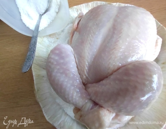 В форму с бортиками высыпать пачку соли слоем и поместить в центр курицу.