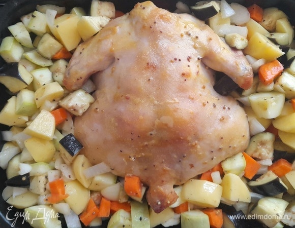 Когда курица будет наполовину готова, достать форму из духовки. Выложить в нее овощи и поставить снова в духовой шкаф. Продолжать запекать до готовности всех ингредиентов.