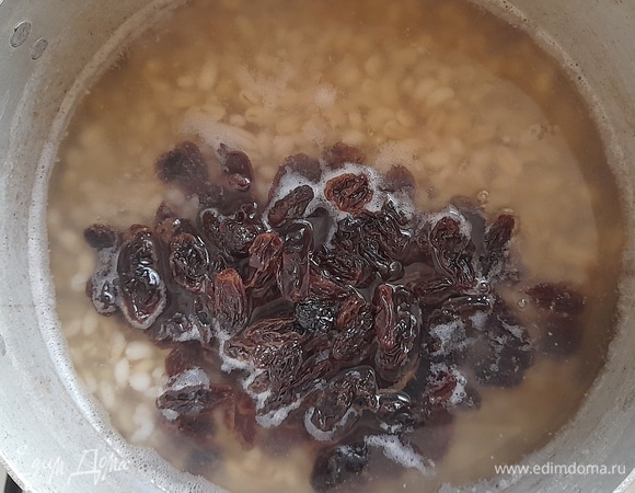 Примерно в середине варки крупы в кастрюлю выложить промытый изюм, перемешать и продолжать варить.