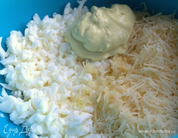 В белки добавить тертый сыр и смешать с ложкой того же майонеза. По желанию выдавить чеснок в этот слой.