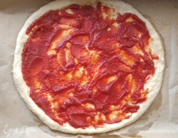 Смазать основу для пиццы томатным соусом, оставляя бортики 1–1,5 см.