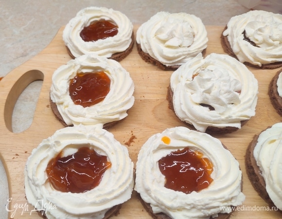 Для крема творог хорошо пробить блендером. Сливки взбить с сахарной пудрой до устойчивых пиков. Если вы сладкоежка, то увеличивайте количество сахарной пудры на свой вкус. Соединить творог со взбитыми сливками. По краю каждого кружка выложить крем, в середину положить любимый джем и сверху закрыть кремом.