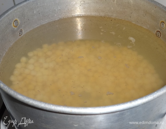 С набухшего нута слить воду. В кастрюлю налить чистой воды, выложить нут, довести до кипения, убавить огонь и варить почти до готовности. На это может уйти от 1 часа до 1 часа 30 минут.