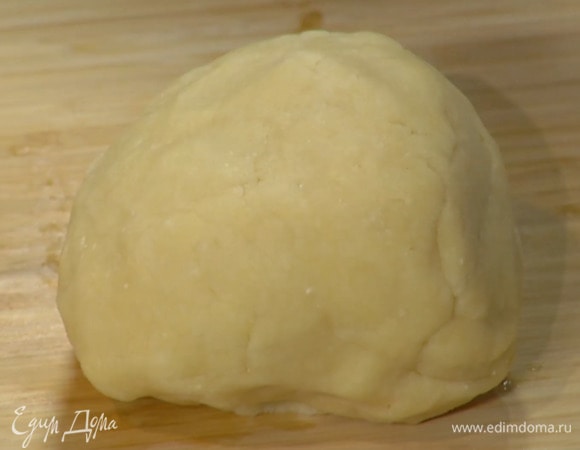 Дно разъемной формы выстелить бумагой для выпечки, смазать ее вместе с бортами оставшимся сливочным маслом и равномерно выложить тесто, сформировав бортики.