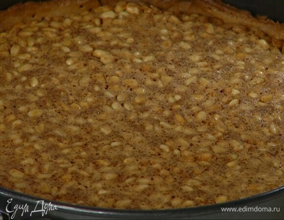 Кедровые орехи перемешать с лимонным кремом, выложить, убрав бумагу с бобовыми, на подпеченный корж, равномерно распределить и выпекать еще около 30 минут.