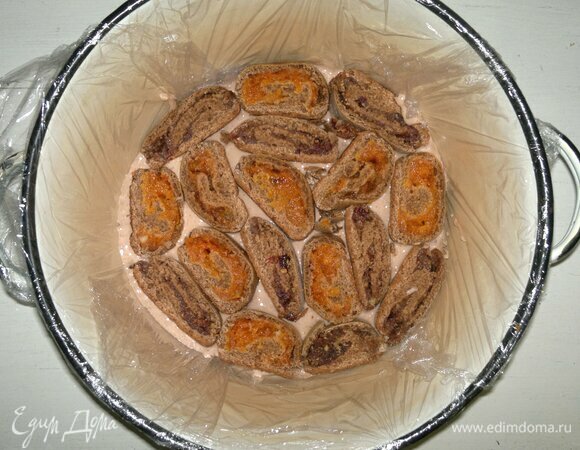 Цилиндрическую или конусообразную форму (кастрюлю) выстелите пищевой пленкой. На дно налейте немного сметанного крема. Выложите слой кусочков рулетов, чередуя их друг с другом. Залейте их частью крема, снова выложите слой рулетов, крем и т. д., пока не закончатся рулеты и крем. Сверху должен быть тонкий слой крема. 