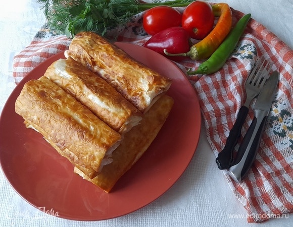 Выложить горячую закуску из лаваша с сосисками на блюдо и подать к столу со свежими овощами и зеленью.