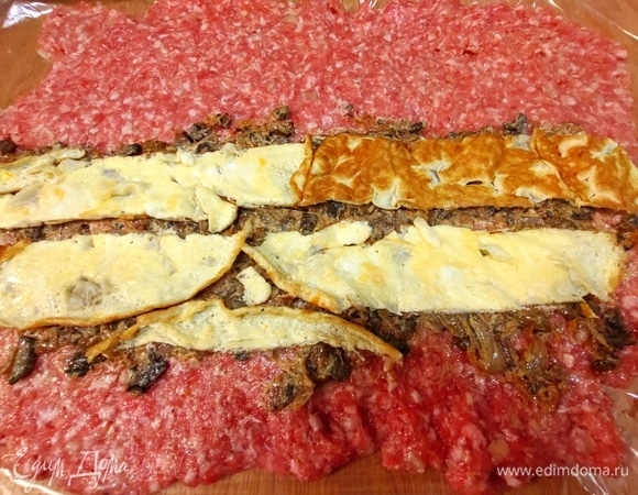 Перенести грибную начинку недалеко от края, сверху накрыть полосками из омлетного блинчика.