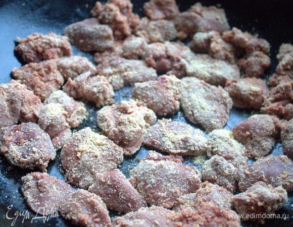 Печенку кусочками обвалять в сухарях и перенести в сковороду, где будем запекать.