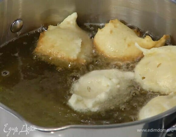 Разогреть в кастрюле масло для фритюра и, ложкой выкладывая в него подошедшее тесто, пожарить пончики и переложить на бумажное полотенце.