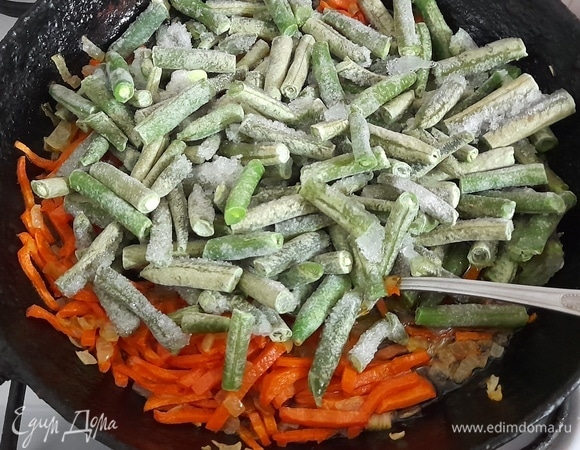 Стручковую фасоль, не размораживая, выложить в сковороду к овощам, перемешать. Обжаривать 5–6 минут.