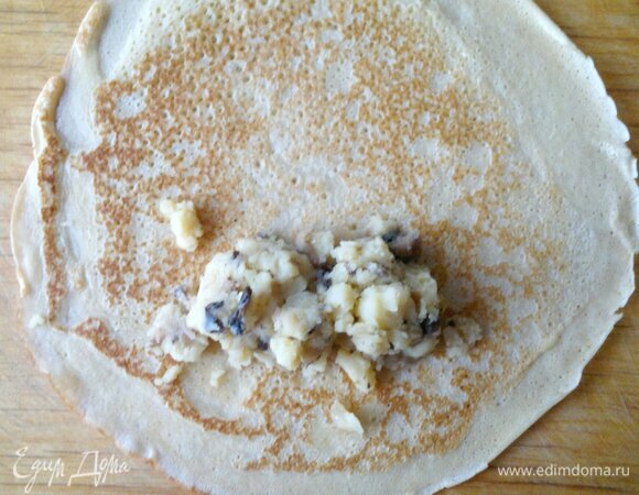 На каждый испеченный блинчик выложить несколько ложек начинки с одного края. Завернуть края блина на начинку и свернуть блинчик рулетом.