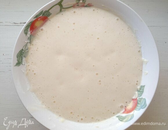 В оставшуюся ряженку всыпать соду, перемешать. Начнется бурная реакция выделения углекислого газа. Добавить смесь в тесто, перемешать. Дать тесту постоять 10–15 минут при комнатной температуре. Если тесто получится густоватым, добавить немного теплой воды.