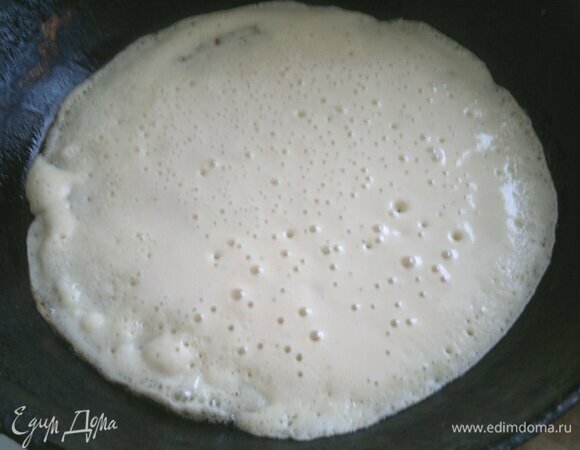 Сковороду разогреть. Перед выпеканием первого блина смазать ее кусочком сала или растительным маслом. Вылить немного теста, распределить по сковороде. Обжарить блинчик сначала с одной стороны.