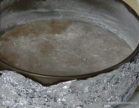 Дно разъемной формы диаметром 25 см выстелить бумагой для выпечки, смазать оставшимся сливочным маслом и присыпать оставшейся мукой. Снаружи дно и бока формы обернуть фольгой.