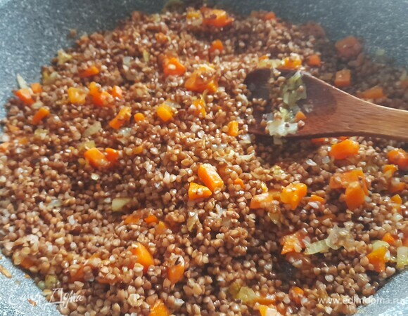 Выложить гречку в сковороду к овощам, перемешать, обжарить вместе пять минут.