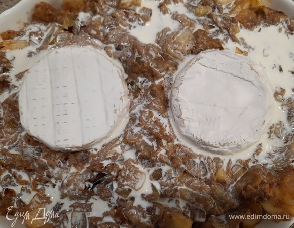 Выложите половину картофеля на дно формы. Сверху распределите луковую смесь и залейте половиной сливок. Положите в форму две половинки камамбера корочкой вверх.