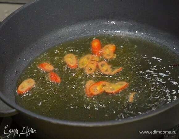 Перец чили нарезать колечками вместе с семенами и выложить в сковороду, где жарился чеснок.