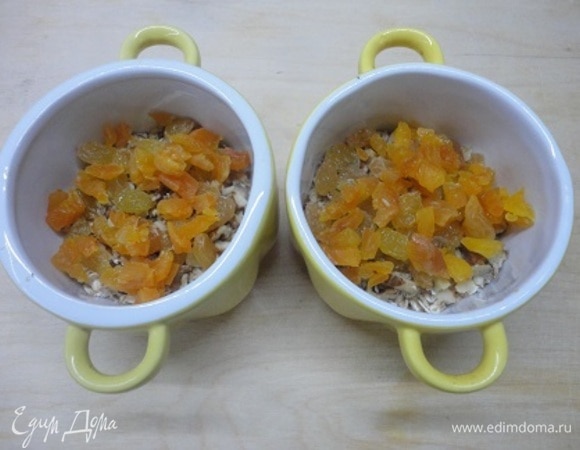 Изюм и курагу промыть. Курагу нарезать кусочками. Добавить в горшочки.