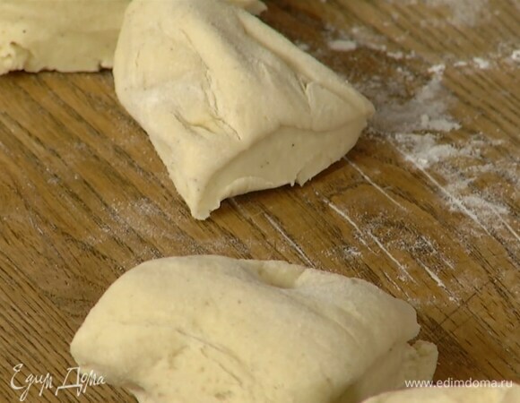 Подошедшее тесто обмять, выложить на присыпанную оставшейся мукой рабочую поверхность, сформировать колбаску и разрезать ее на 8 частей.