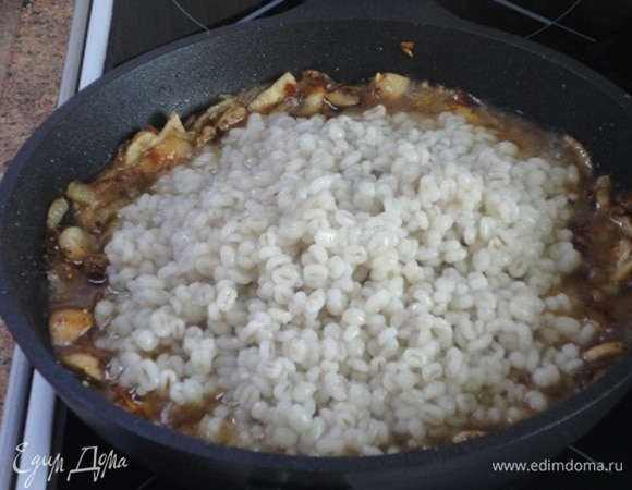 В сковороду к жареным с луком шампиньонам выложить перловку вместе с остатками воды и перемешать ложкой. Прогреть 10–15 минут на среднем огне, затем снять с плиты.
