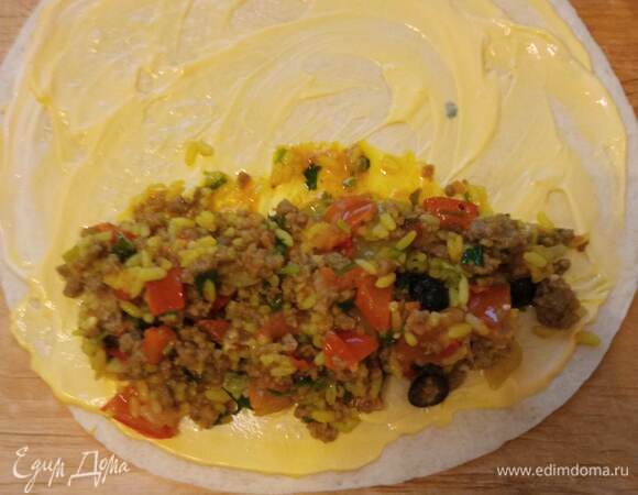 Взять лепешку, смазать ее соусом. На один край выложить немного начинки из фарша с рисом и овощами. Аккуратно свернуть лепешку трубочкой. Можно закрыть с боков, как сделала я, но это необязательно. Таким образом завернуть все лепешки.