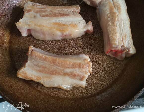 Свиные ребра промываем, обсушиваем бумажными полотенцами и режем на куски по линии ребер. Обжариваем до легкой корочки на разогретой сковороде без масла. Перекладываем в кастрюлю, заливаем горячей водой и варим 1 час после закипания. По необходимости снимаем пену. Обычно после обжарки мяса ее очень мало.