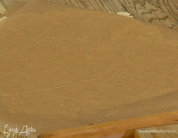 Поместить тесто между двумя листами бумаги для выпечки и раскатать в пласт.