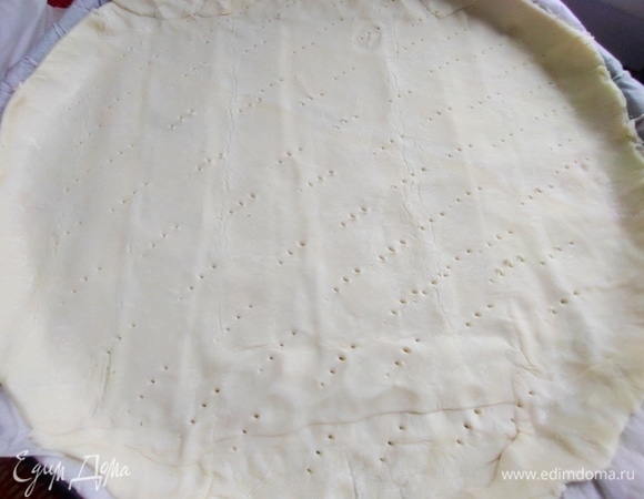 Выкроить из теста круг по форме, дно наколоть вилкой. У меня ушла вся упаковка теста, только углы обрезала. Продается прямо на пергаменте, что очень удобно — раскрутил и перенес в форму.