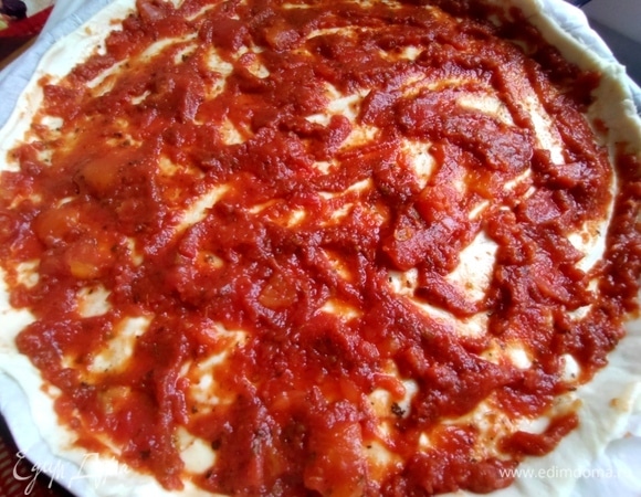 Процедить томаты в собственном соку, размять и пюре нанести на тесто.