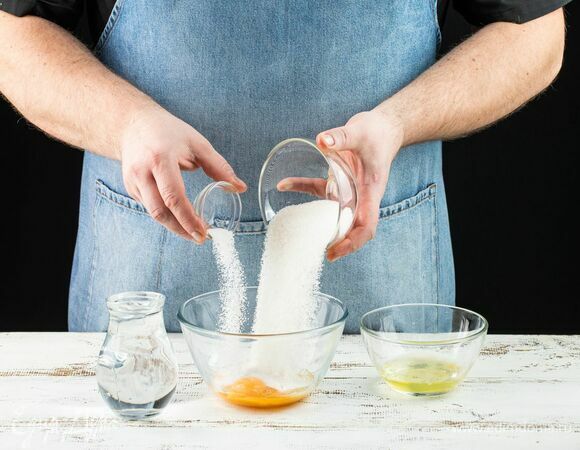 Смешайте в емкости 2 яичных желтка, 1 белок (второй оставьте для смазывания выпечки), сахар, ванилин и воду. Интенсивно мешайте до полного растворения сахара.