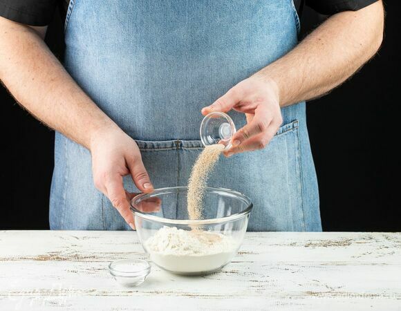 В глубокую емкость просейте муку, добавьте соль и дрожжи, перемешайте сухие ингредиенты.
