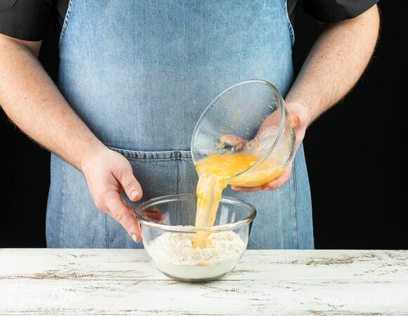Влейте к сухим ингредиентам яичную смесь и замешайте тесто. Удобнее вливать жидкость в несколько этапов.
