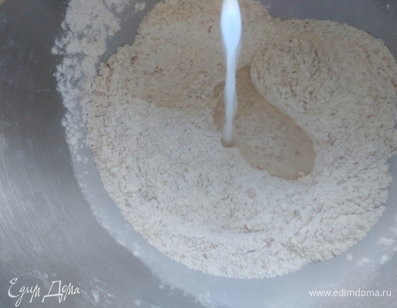 В кефире размешать соду, разбавить теплой водой и влить в сухую смесь.