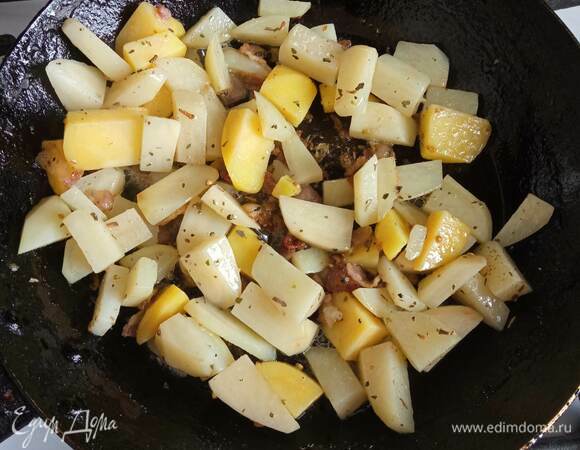 На другой сковороде без масла обжариваем пару минут мелко нарезанный шпик. Когда шпик даст жир, добавляем нарезанный кубиком или брусочками картофель. Посыпаем орегано. Жарим минут 5–7 до полуготовности.