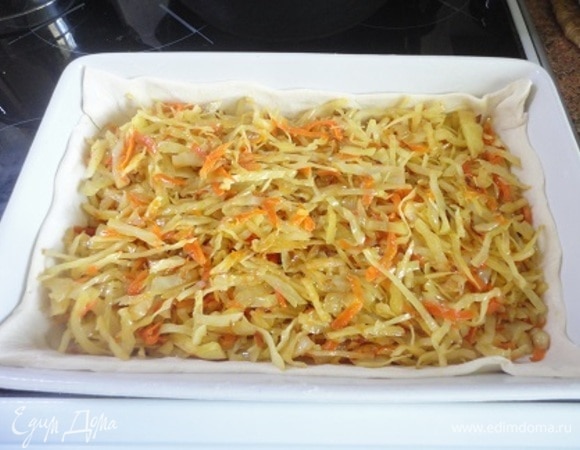 Форму для выпечки смазать маслом. Один пласт теста раскатать и выложить на дно формы, формируя бортики. Выложить начинку.