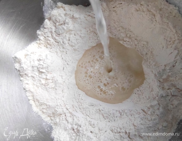 Сделать в муке ямку и перелить воду. Муки может понадобиться еще 1–2 ложки.