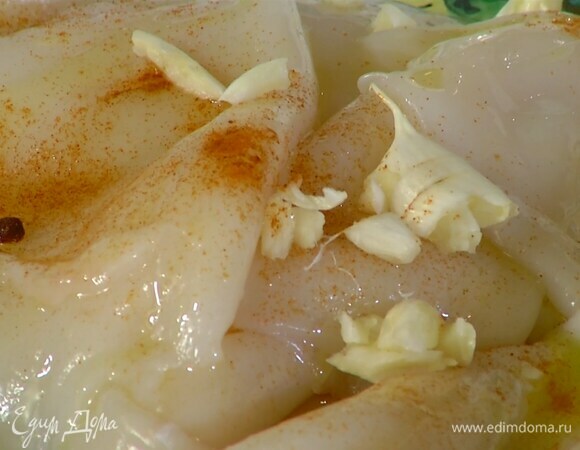 Тушки кальмаров посыпать паприкой, полить 1 ст. ложкой оливкового масла, добавить измельченный чеснок, посолить, поперчить и перемешать.