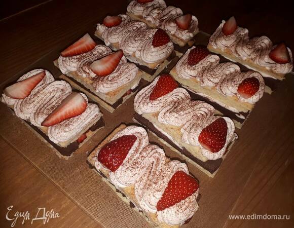 Накройте вторым слоем бисквита, нанесите остальной клубничный ганаш сверху, посыпьте какао и украсьте клубникой.