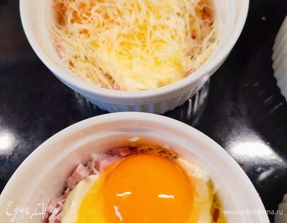 В каждую формочку сверху разбить по яйцу и посыпать сверху тертым сыром.