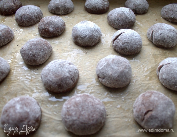Из податливого теста скатать небольшие шарики и слегка приплюснуть на смазанном пергаменте.