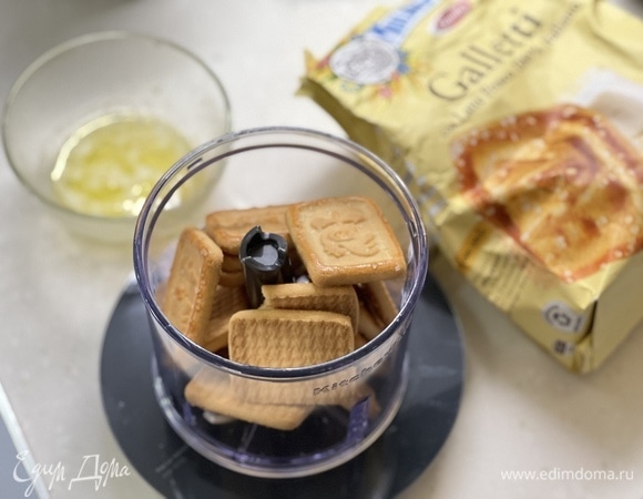 В небольшой миске смешайте измельченное печенье и растопленное масло. Смесь должна иметь консистенцию мокрого песка. Выложите смесь в форму для запекания, утрамбуйте. 