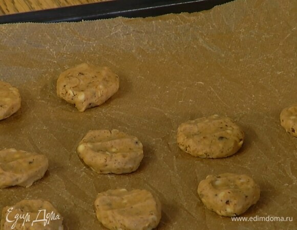 Сформировать из теста небольшие лепешки и выложить на выстеленный бумагой для выпечки противень.