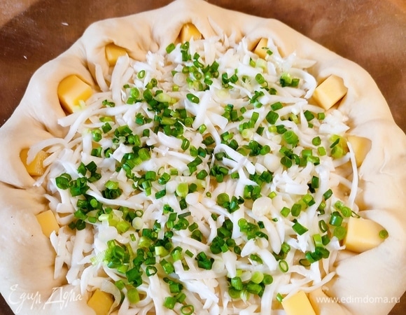 Середину пирога смазать оливковым маслом, посыпать тертой моцареллой и зеленым луком.